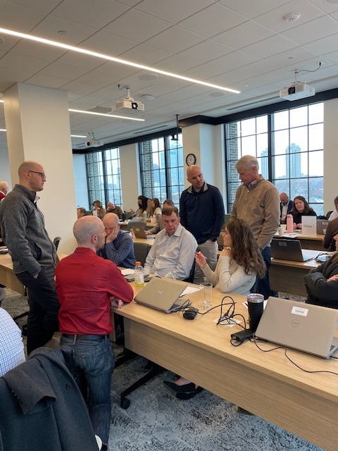 Standing group huddle around a working table during a Clustr session